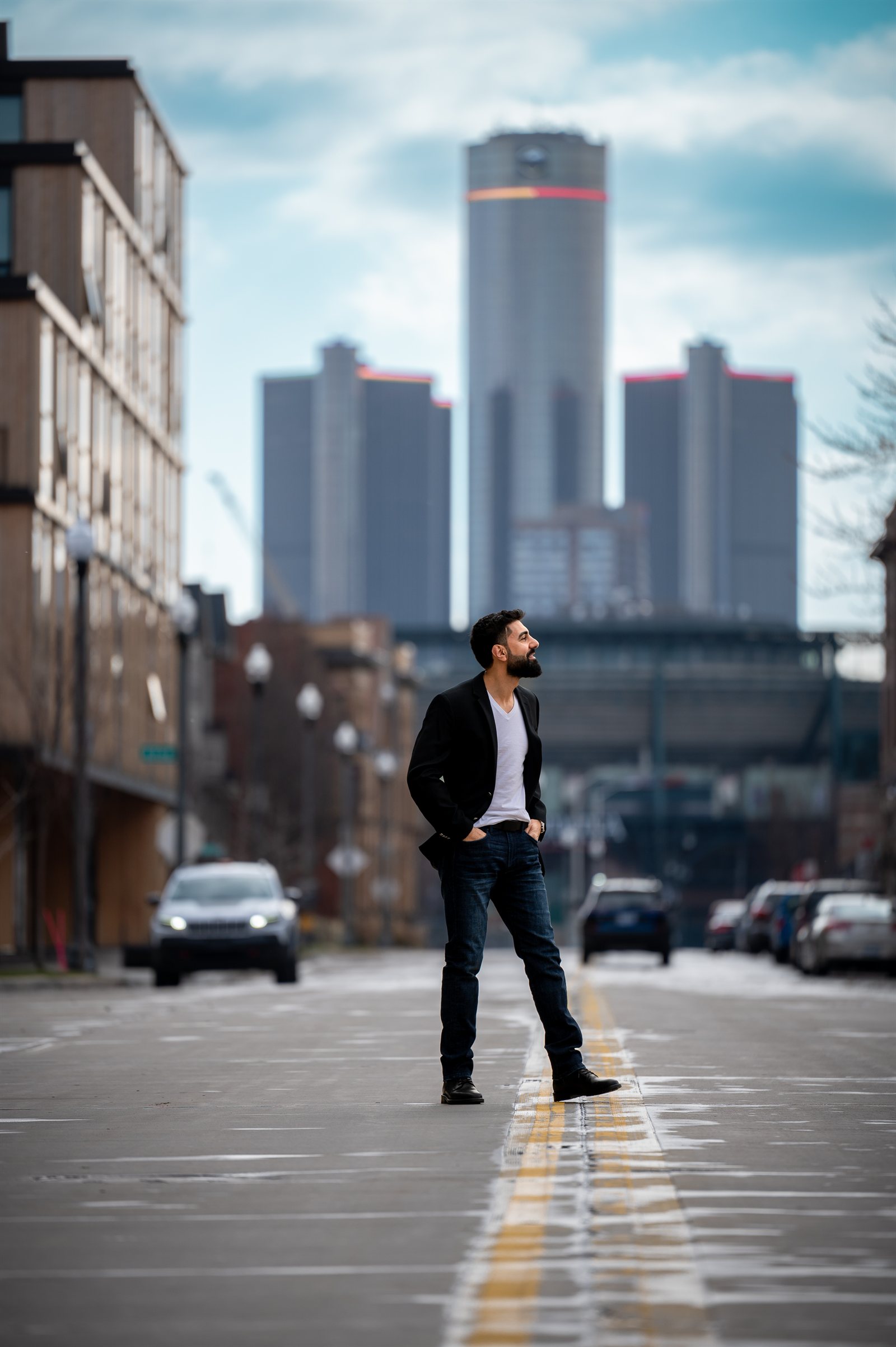 Ahmad Bazzi standing in an empty Detroit street, the Renaissance Center rising behind him.