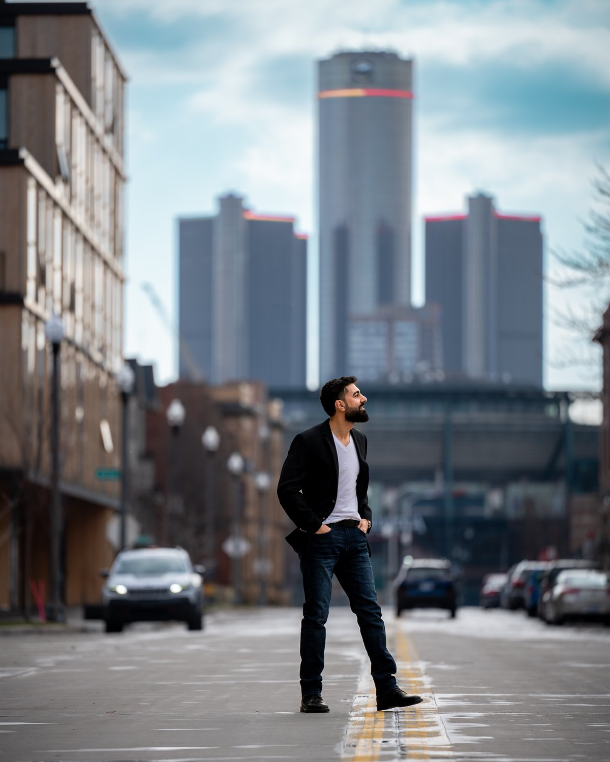 Ahmad Bazzi standing in an empty Detroit street, the Renaissance Center rising behind him.